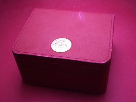 Omega Uhren-Box aus Leder in rot mit Umkarton, 16cm x 14cm x 9cm, gebraucht, weist Lager- und Gebrauchsspuren auf 